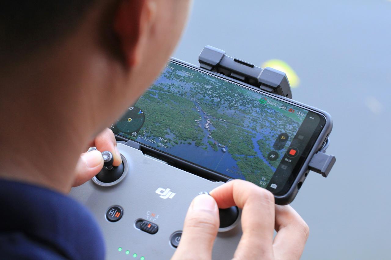 Person controlling drone with smartphone and controller